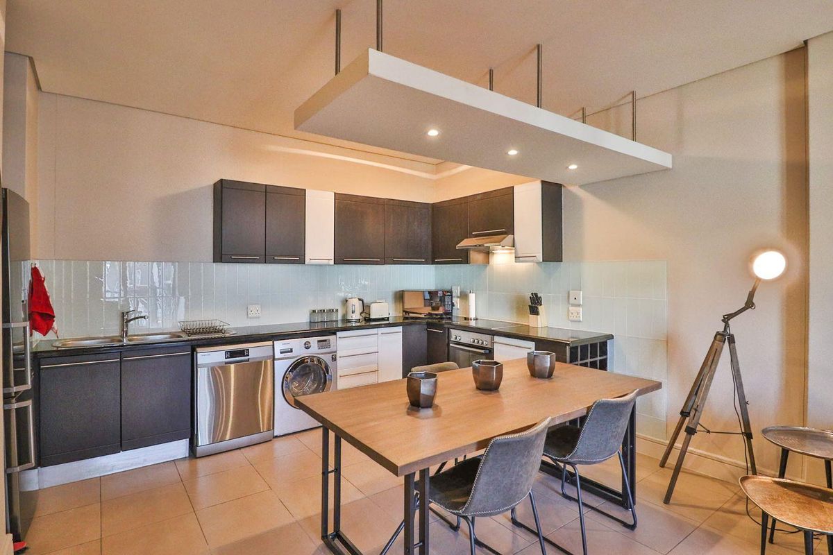 Modern open-plan kitchen featuring dark and white cabinetry, integrated appliances, tiled backsplash, and a distinctive suspended ceiling feature with recessed lighting.