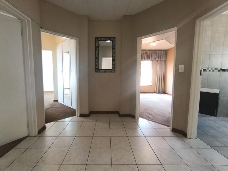 A central hallway featuring neutral tiled flooring, providing access to multiple rooms including a bedroom and bathroom area.