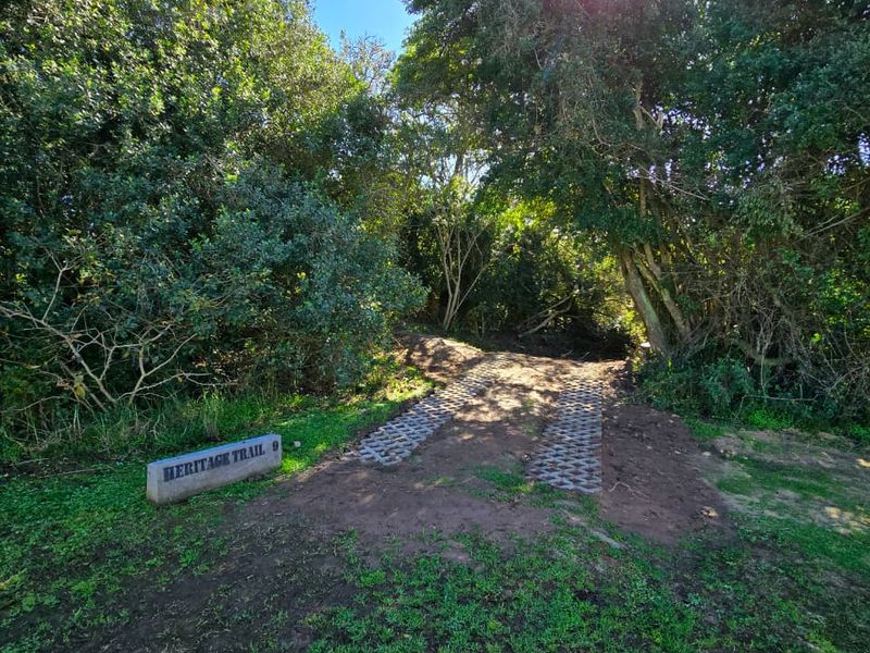 A view of the property entrance featuring paved driveway tracks and a stone sign marking the location.