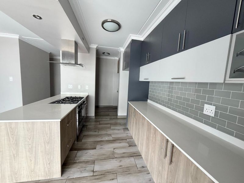 Modern kitchen featuring two-tone cabinetry, stone countertops, a gas hob with extractor, and a stylish subway tile backsplash in an open-plan layout.