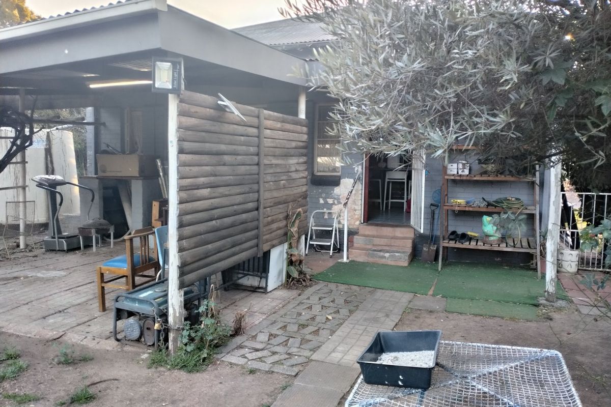 Rear exterior view featuring a covered patio area with brick paving, timber privacy screen, and direct access to the main dwelling.