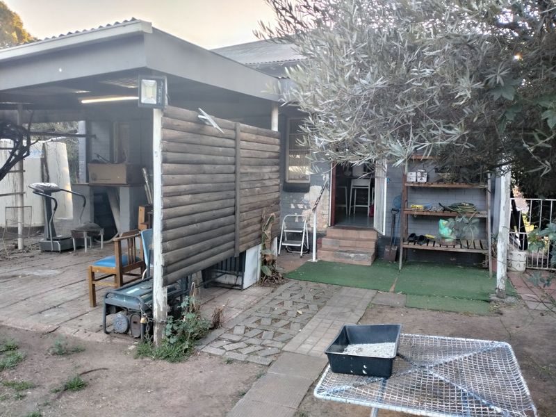 Rear exterior view featuring a covered patio area with brick paving, timber privacy screen, and direct access to the main dwelling.
