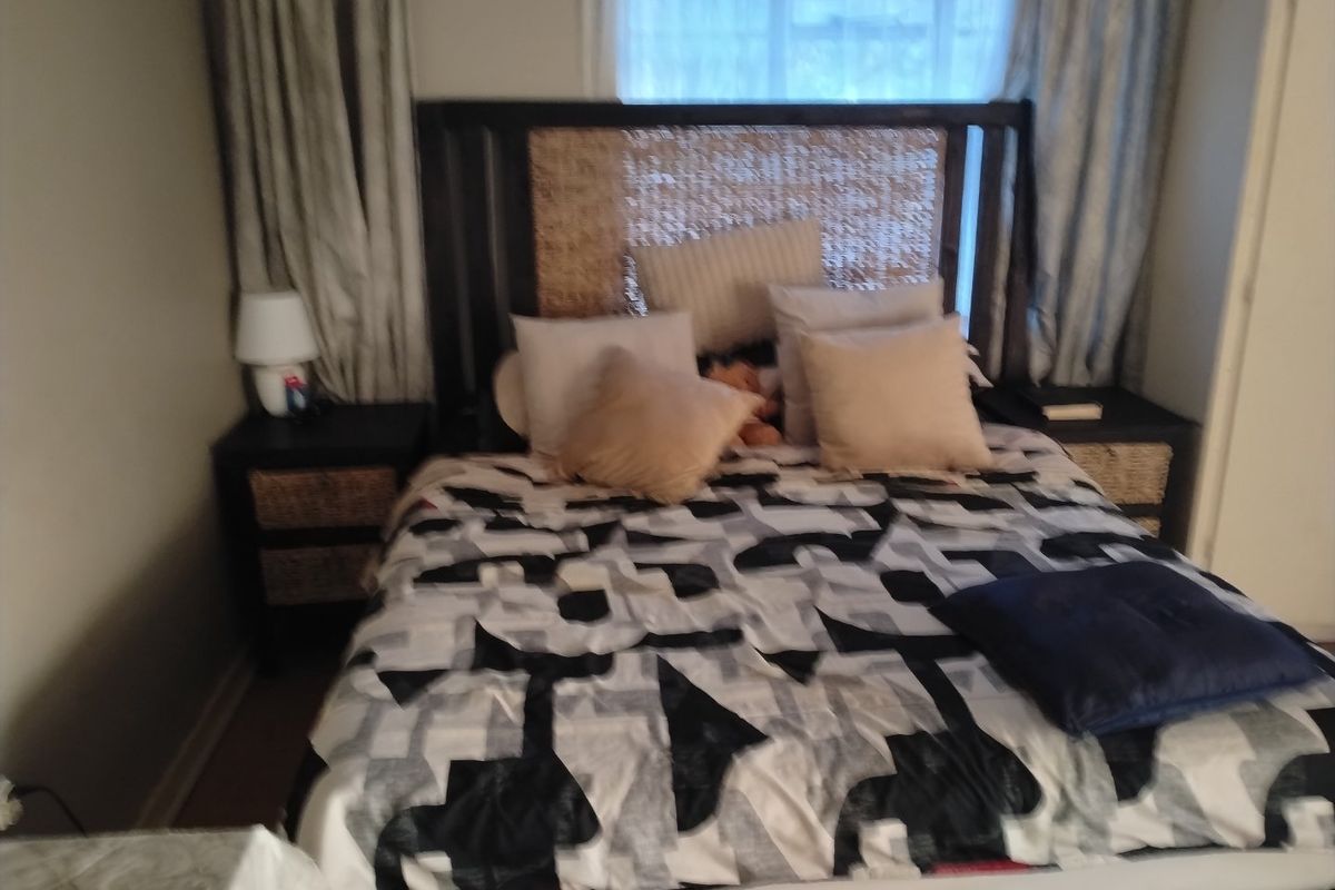 A bedroom featuring a bed with a woven headboard and curtains framing the window.