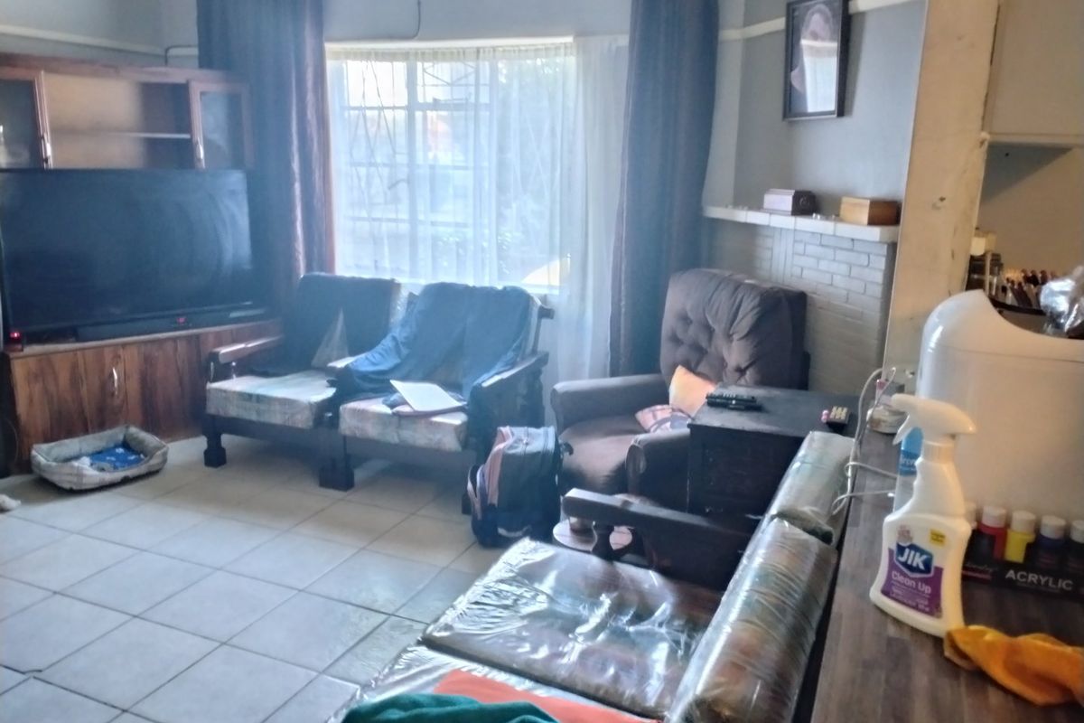 A living room featuring tiled flooring and a brick fireplace, offering a functional space with potential for cosmetic updates.