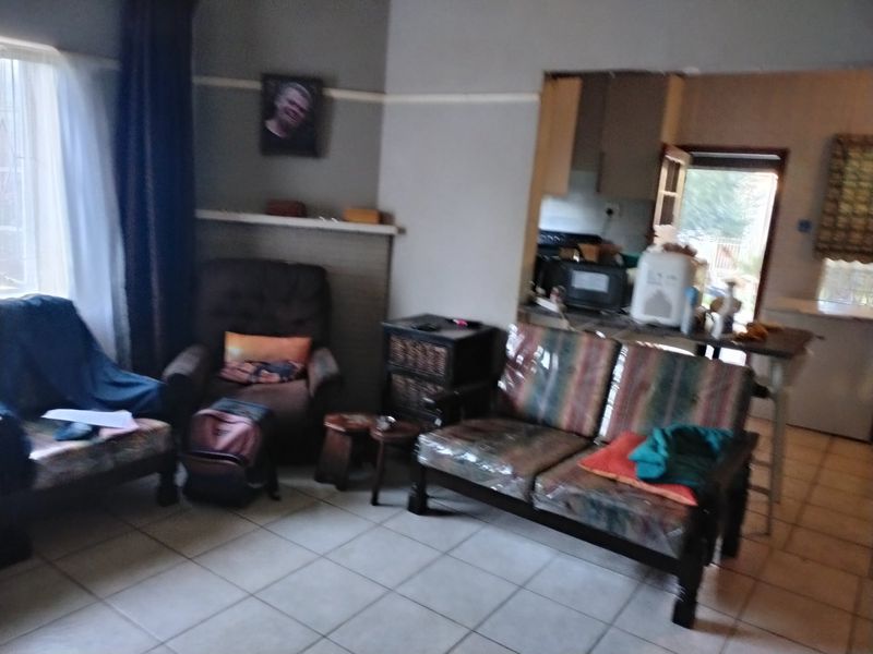 Open plan living area featuring tiled flooring and a connected kitchen space with a breakfast bar.