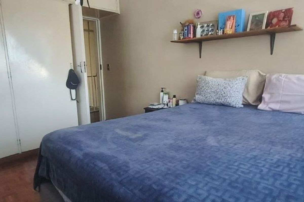 A bedroom featuring built-in cupboards and parquet flooring, offering a functional space with potential for cosmetic updates.