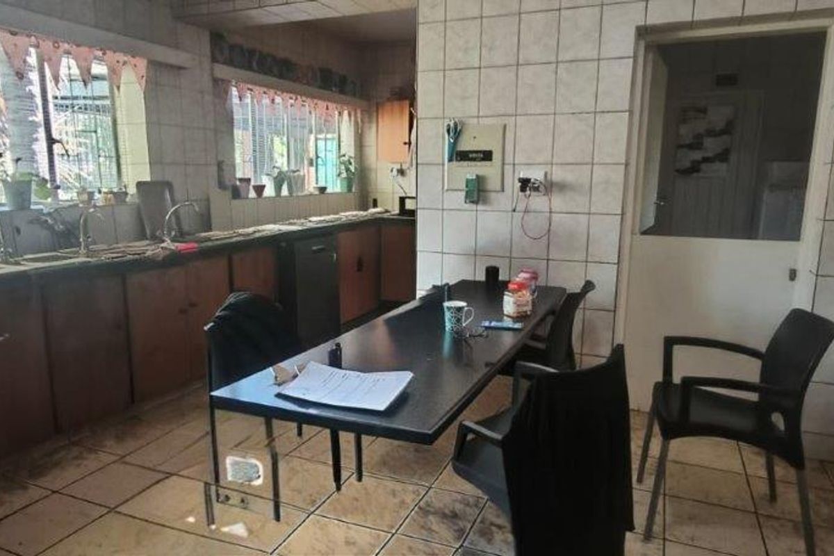A dated kitchen featuring tiled walls and flooring, extensive built-in cabinetry, and a double sink, offering significant potential for modernization and renovation.