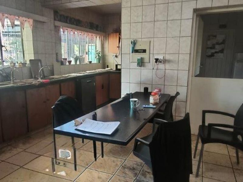 A dated kitchen featuring tiled walls and flooring, extensive built-in cabinetry, and a double sink, offering significant potential for modernization and renovation.