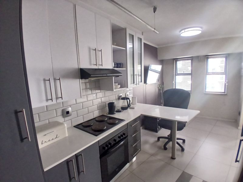Modern kitchen featuring two-tone cabinetry, subway tile backsplash, integrated electric hob and oven, and a convenient breakfast bar area.