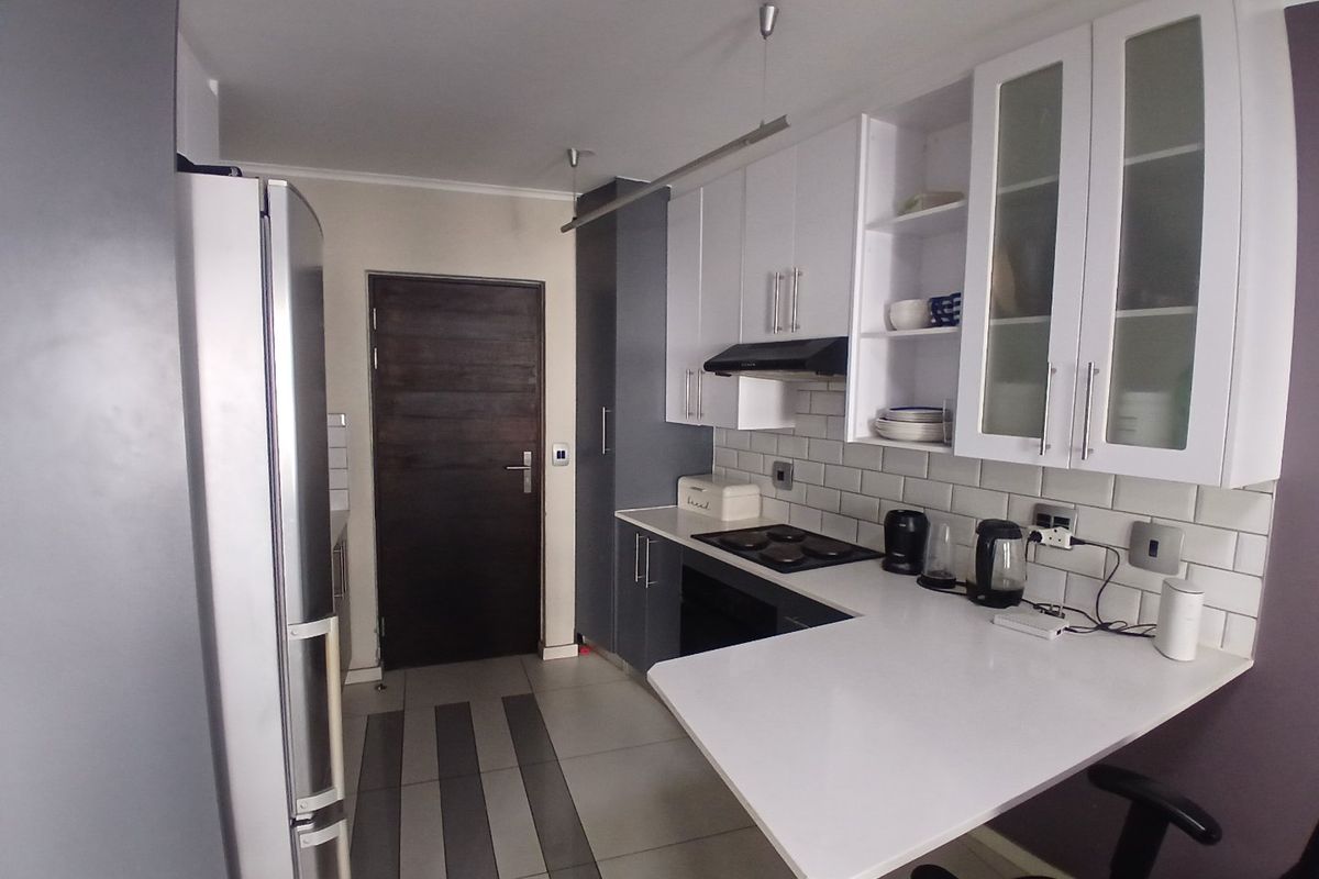 A modern kitchen featuring white cabinetry, subway tile backsplash, stone countertops, and integrated appliances, providing a functional and clean cooking space.
