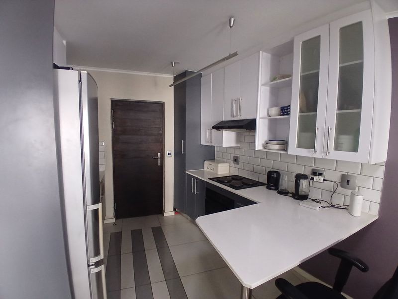 A modern kitchen featuring white cabinetry, subway tile backsplash, stone countertops, and integrated appliances, providing a functional and clean cooking space.