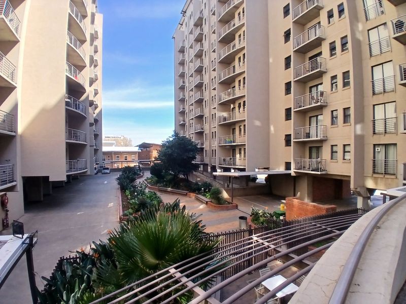 View of the apartment complex courtyard featuring landscaped gardens, paved driveway, and multiple levels of private balconies.
