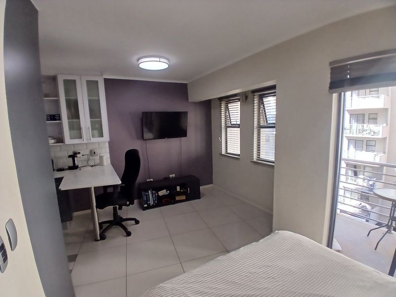 Open-plan living area featuring tiled floors, built-in cabinetry, and direct access to a private balcony through sliding glass doors.