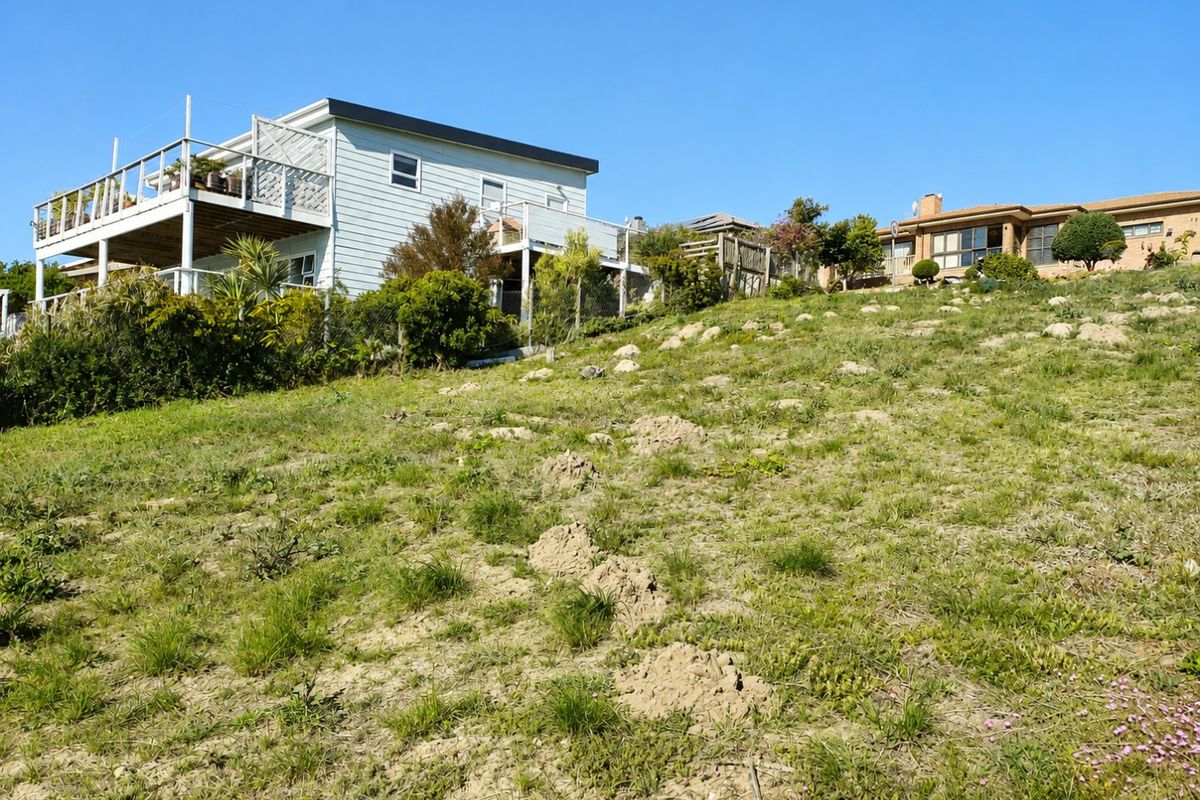 A view of the sloped residential land with existing neighboring properties visible in the background.