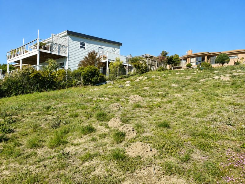 A view of the sloped residential land with existing neighboring properties visible in the background.