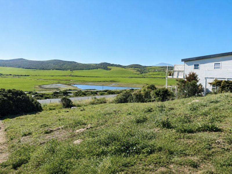 A scenic view overlooking a green valley, wetlands, and distant hills from the elevated residential land.