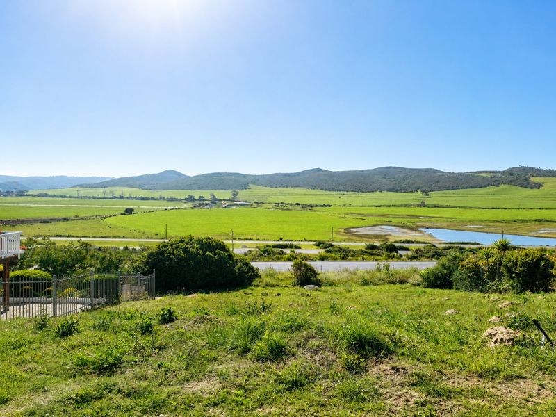 Expansive scenic view overlooking green fields, wetlands, and distant hills from the elevated residential plot.