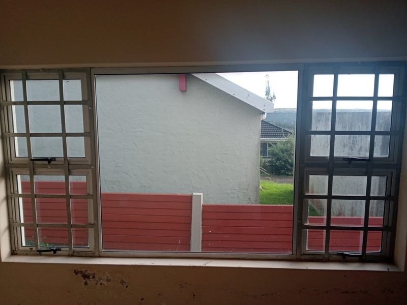 Interior view of a bedroom featuring aluminium window frames with security burglar bars, showing signs of wall surface wear and peeling paint.