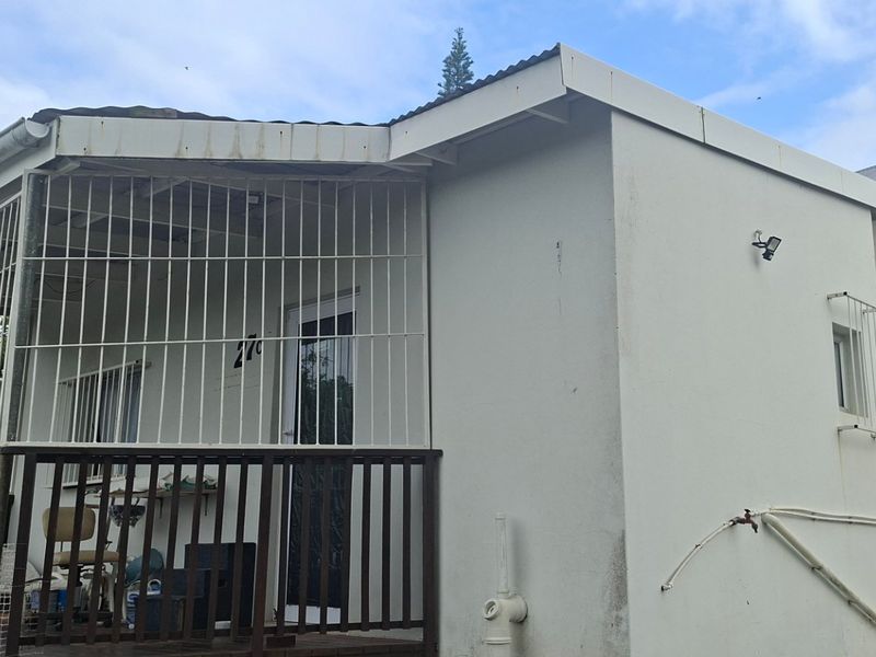 Front exterior view of the property featuring a covered deck area with security gates and basic exterior finishes.