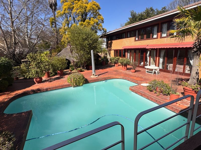 A spacious outdoor pool area featuring a brick-paved patio, a well-maintained swimming pool, and direct access to the home through sliding glass doors.