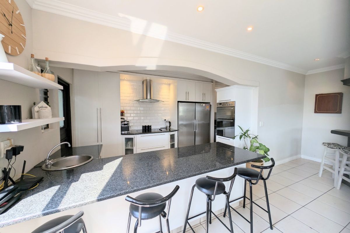 Modern kitchen featuring granite countertops, subway tile backsplash, built-in oven, and an integrated breakfast bar, creating a functional and stylish cooking space.