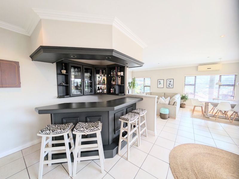A well-maintained built-in bar area featuring custom cabinetry, a dark countertop, and recessed lighting, seamlessly integrated into an open-plan living space.