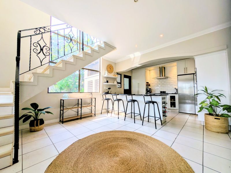 Spacious open-plan kitchen and living area featuring a modern kitchen island, subway tile backsplash, and an elegant staircase with a wrought iron balustrade.