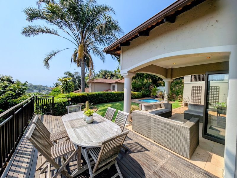 Spacious covered patio featuring timber decking, recessed lighting, and direct access to the garden and pool area, offering a seamless indoor-outdoor living experience.