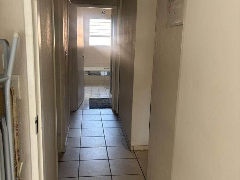A functional hallway featuring tiled flooring and an integrated electrical distribution board, providing access to adjacent rooms.