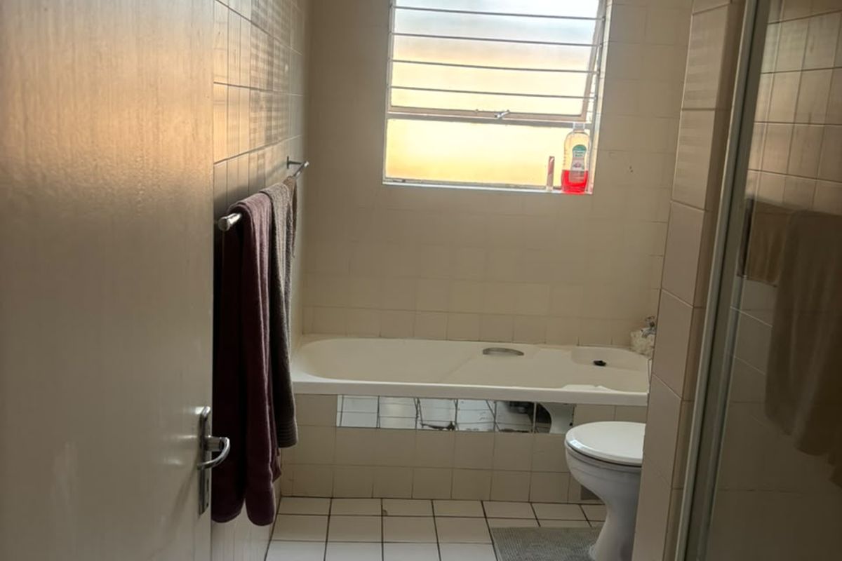A dated bathroom featuring a standard bathtub, toilet, and tiled finishes, requiring modernization to improve its aesthetic and functional appeal.