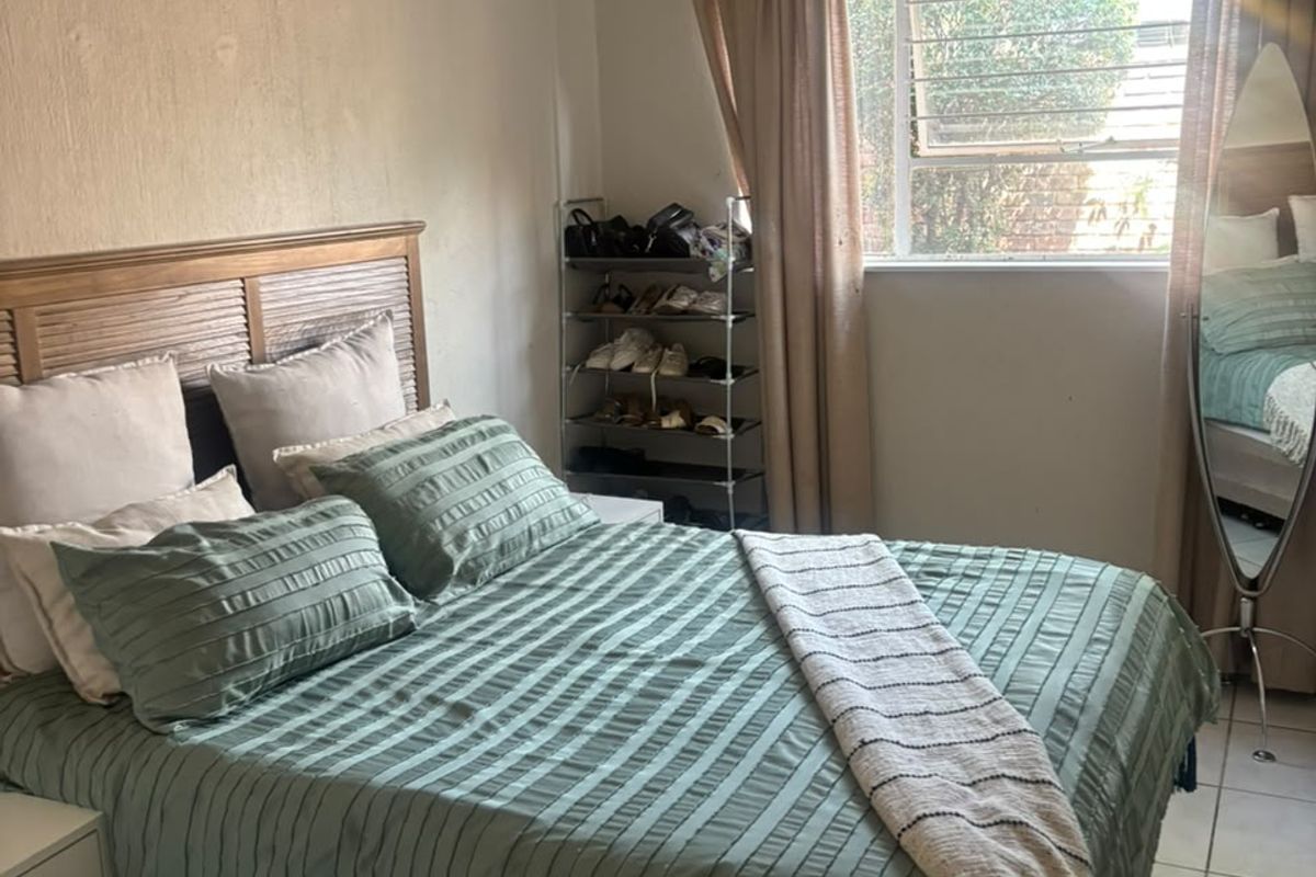 A functional bedroom featuring tiled flooring and a window with security bars, offering a neutral base for potential interior updates.
