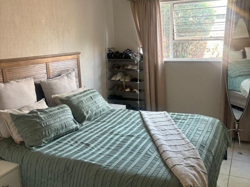 A functional bedroom featuring tiled flooring and a window with security bars, offering a neutral base for potential interior updates.