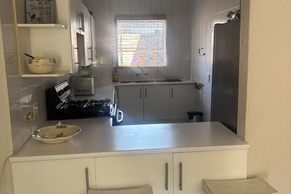 Functional kitchen featuring white cabinetry, a gas stove, tiled backsplash, and a convenient breakfast bar pass-through to the living area.