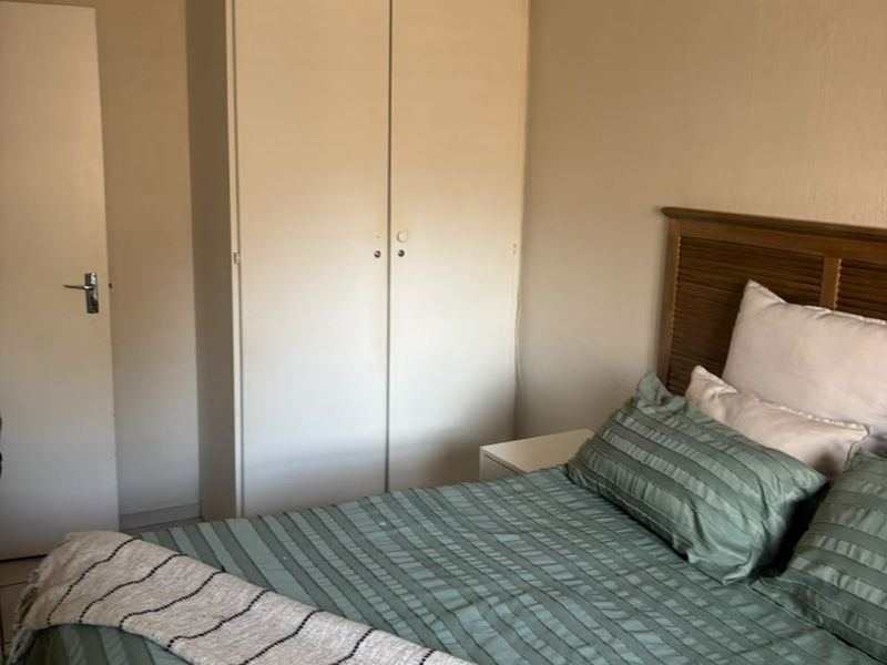 A functional bedroom featuring a built-in wardrobe, tiled flooring, and a timber-look ceiling, offering a neutral base for personalization.