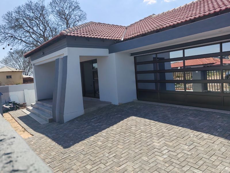 Modern front elevation featuring a paved driveway, covered entrance porch, and a contemporary sectional garage door with a tiled roof.