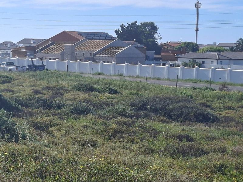 A view of the vacant residential land showing surrounding neighborhood infrastructure, perimeter walling, and road access.
