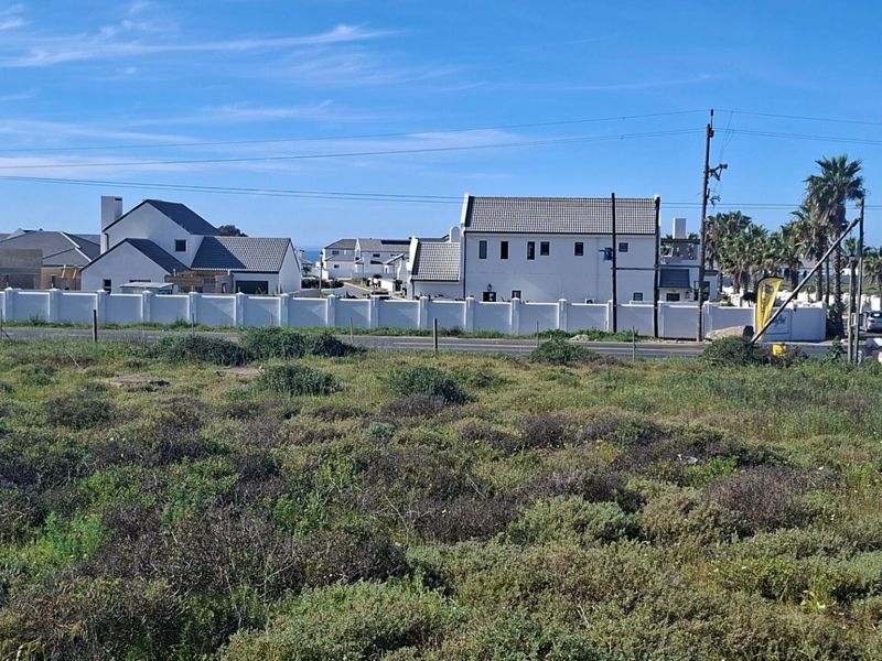 A view of a vacant residential plot with surrounding neighborhood infrastructure and perimeter walling visible in the background.
