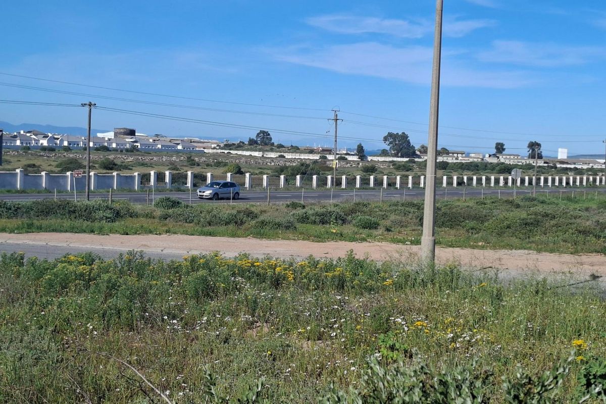 A view of the vacant residential land showing the adjacent road, perimeter fencing, and surrounding utility infrastructure.
