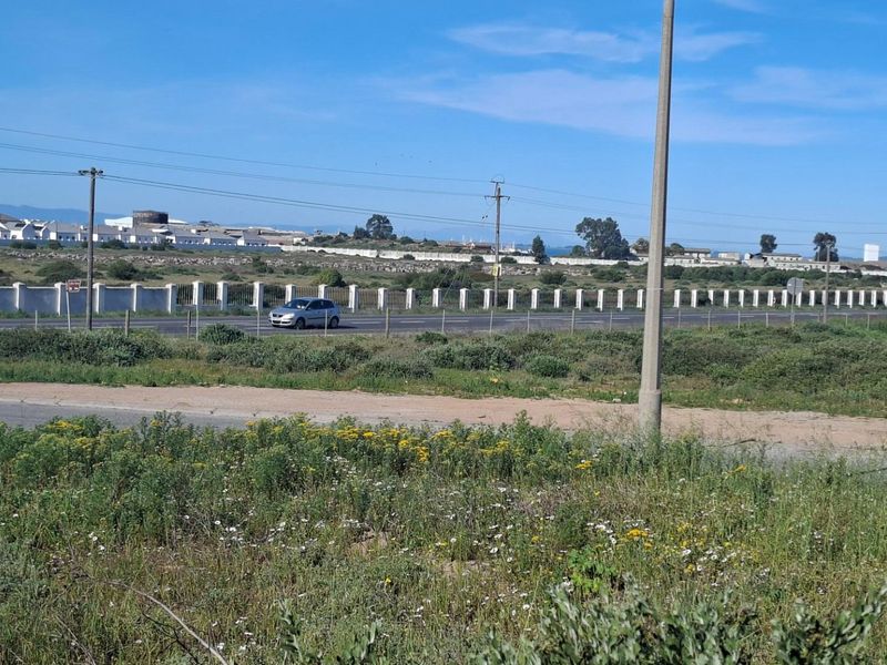 A view of the vacant residential land showing the adjacent road, perimeter fencing, and surrounding utility infrastructure.