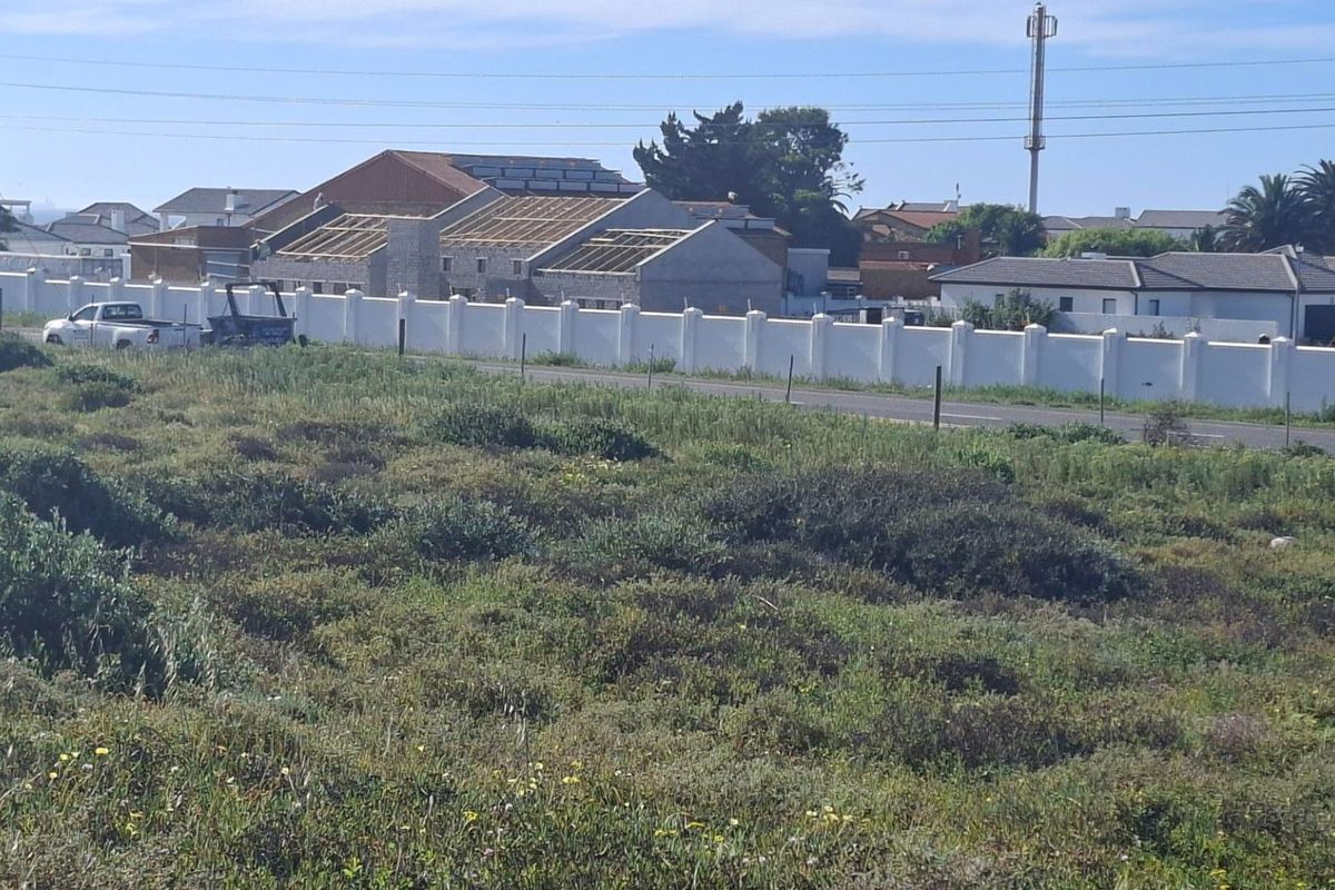 A view of the vacant residential land showing surrounding neighborhood infrastructure, perimeter walling, and road access.