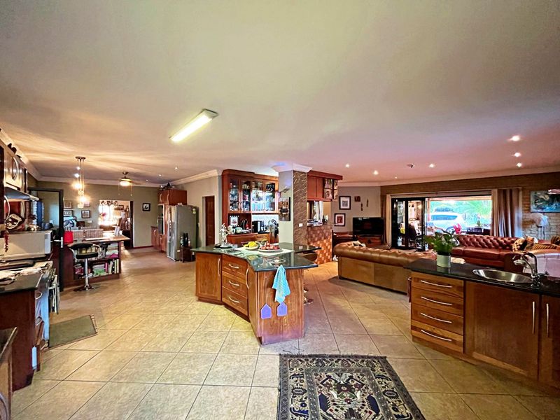 Spacious open-plan living area featuring a large kitchen with granite countertops, wooden cabinetry, and seamless flow to the lounge and outdoor access.