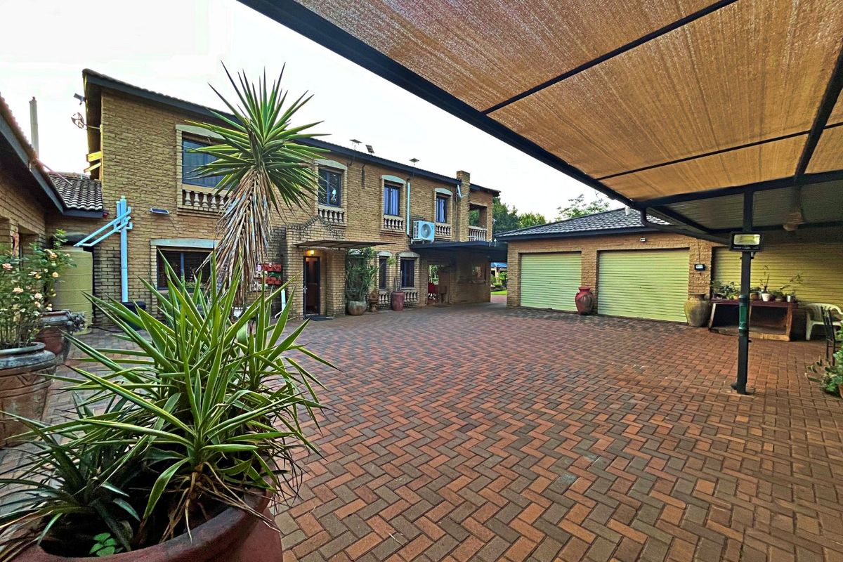 Spacious paved courtyard area featuring a large shade cloth canopy, facebrick exterior walls, and access to a double garage.