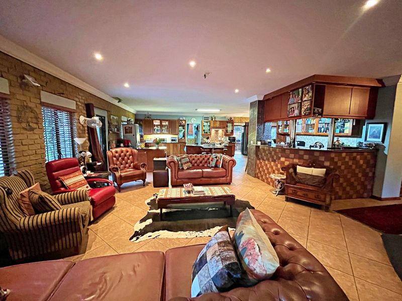 Spacious open-plan living area featuring a built-in bar, tiled flooring, exposed brick accents, and a connected kitchen with wooden cabinetry.