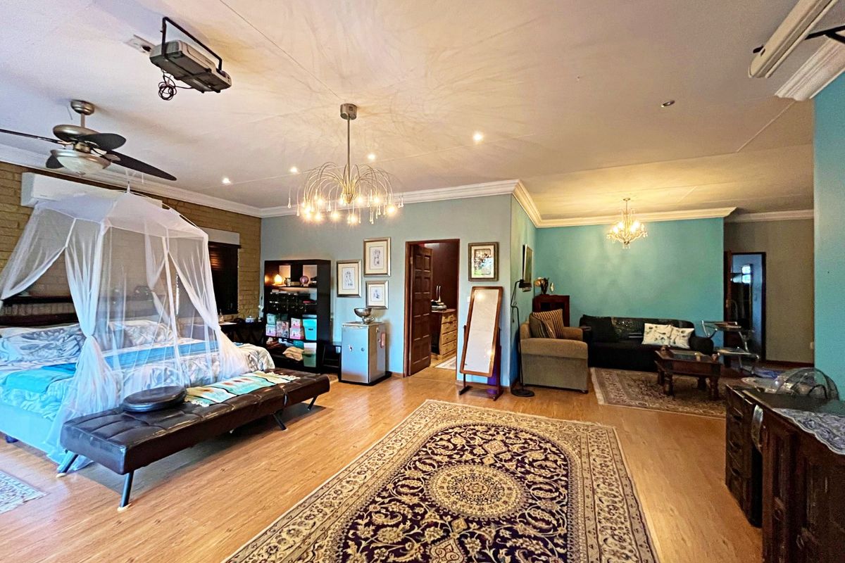 Spacious bedroom featuring laminate flooring, recessed lighting, dual chandeliers, ceiling fan, and an integrated air conditioning unit.