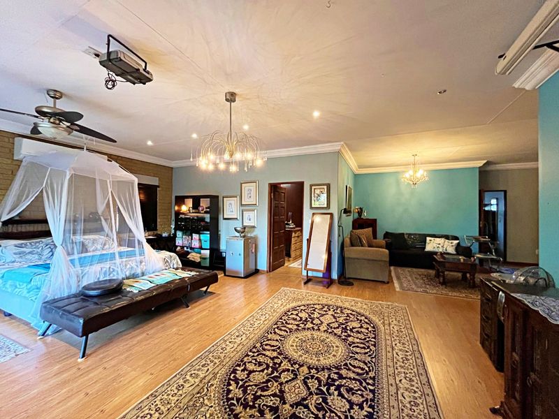 Spacious bedroom featuring laminate flooring, recessed lighting, dual chandeliers, ceiling fan, and an integrated air conditioning unit.