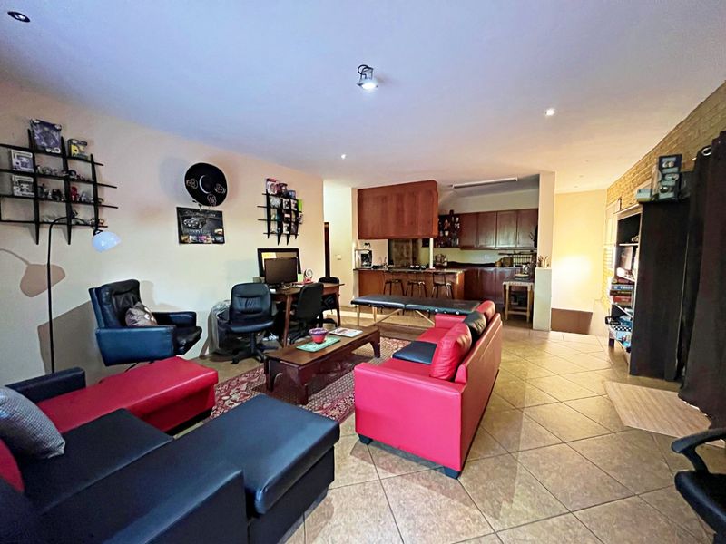 Open-plan living area featuring tiled flooring, recessed lighting, and an integrated kitchen with a breakfast bar and wooden cabinetry.