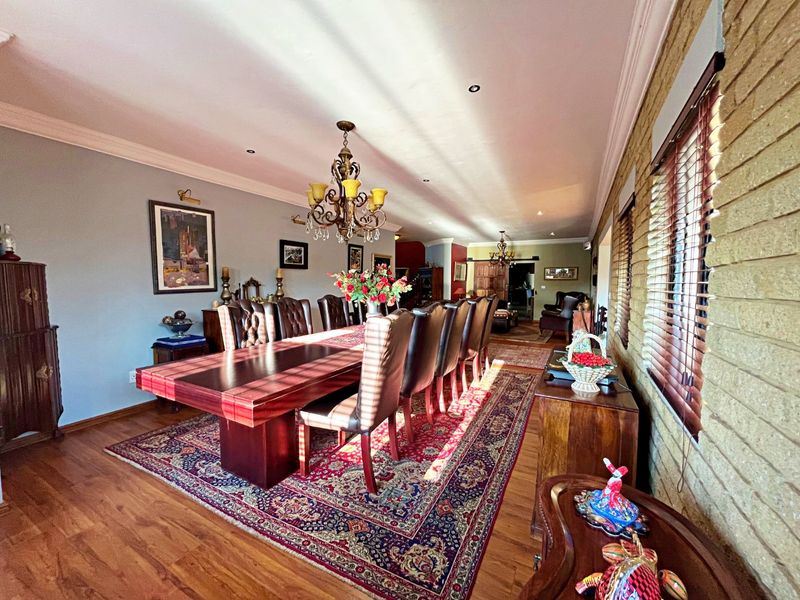 Spacious dining room featuring warm laminate flooring, an exposed brick feature wall, and recessed downlighting, creating a classic and inviting atmosphere.