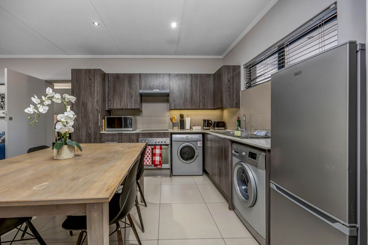Modern kitchen featuring dark wood cabinetry, stone countertops, integrated appliances, and tiled flooring, offering a functional and contemporary cooking space.