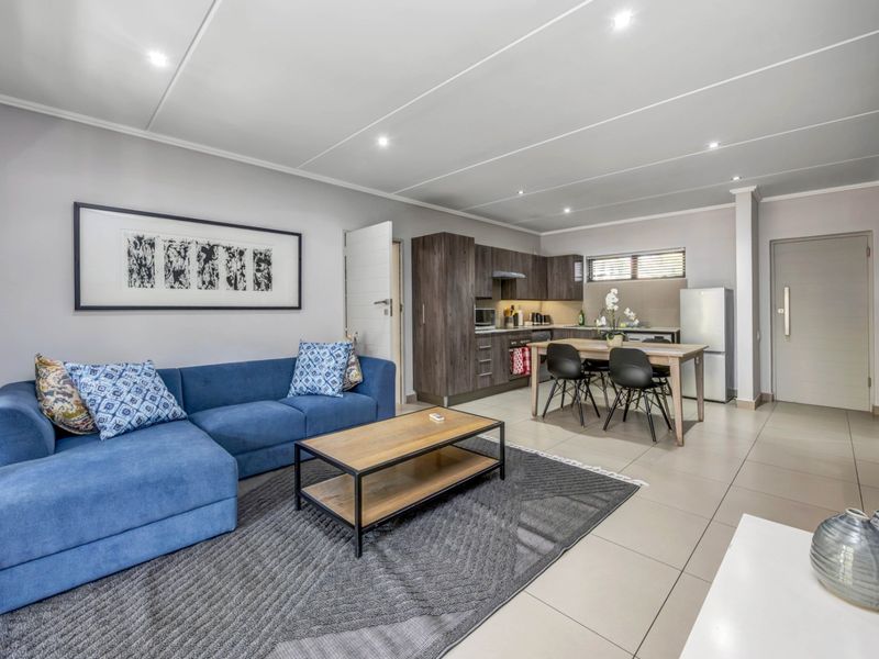 Modern open-plan living area featuring tiled floors, recessed lighting, and a contemporary kitchen with built-in cabinetry and integrated appliances.