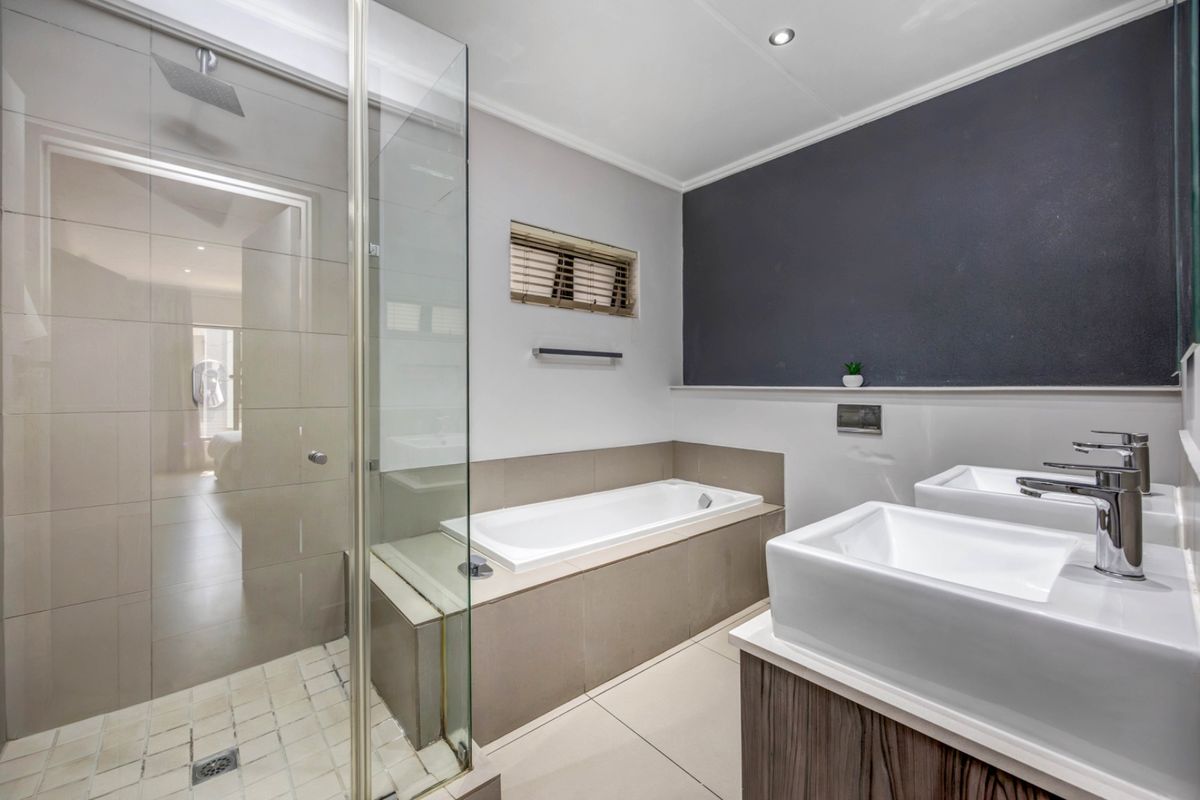 Modern bathroom featuring a glass-enclosed shower, built-in bathtub, and a sleek double vanity with contemporary fixtures.